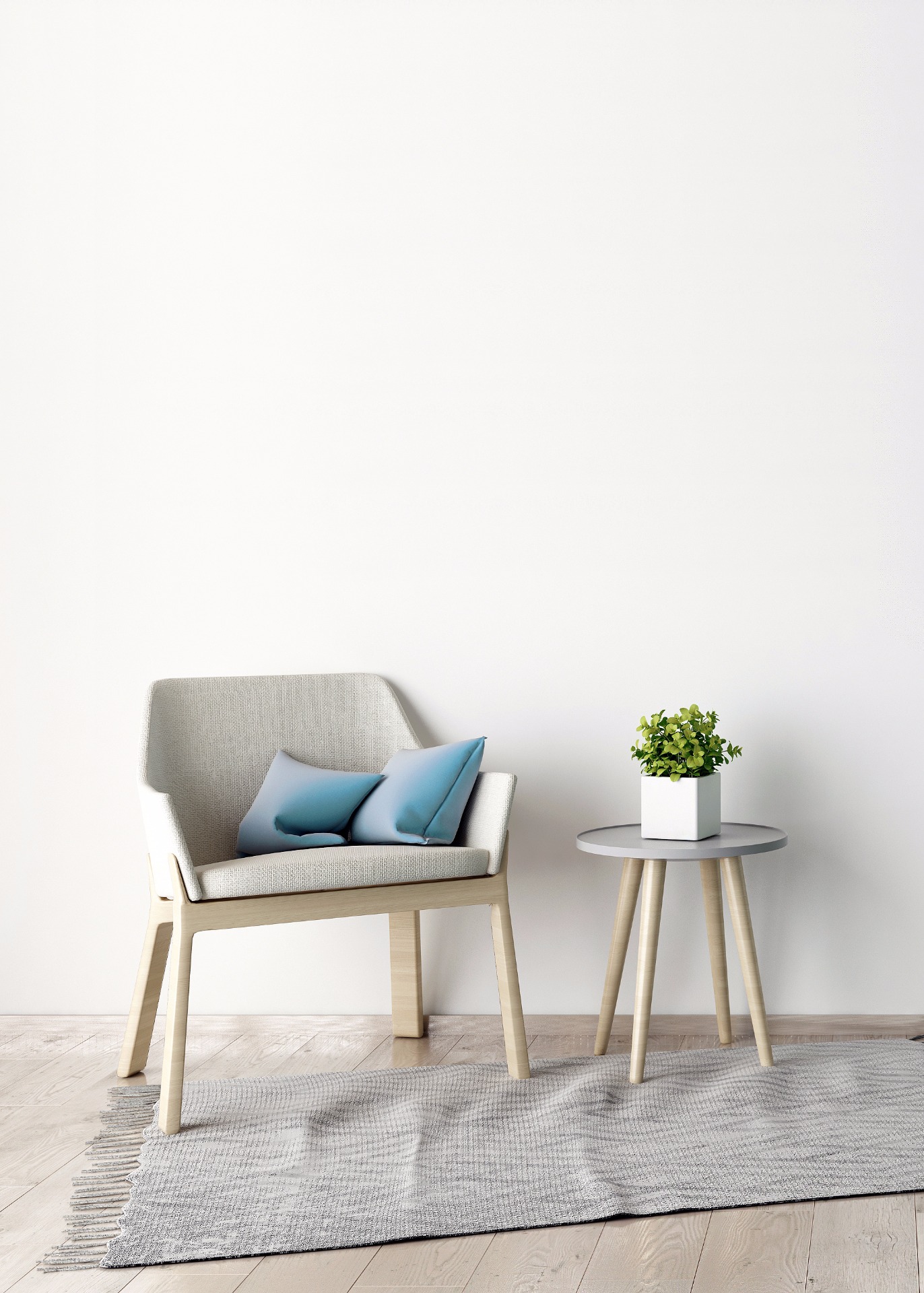 Light gray armchair with blue pillows beside a small round table holding a potted green plant.